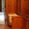 This Walk-In closet made from Red Oak and Natural Maple interiors features matching paneled walls, drawer base cabinets, roll out hampers, plenty of clothes hanging space, adjustable shelving and shoe cubbies.Also, a full length mirror, open glass shelf cabinet & pull out folding area. 